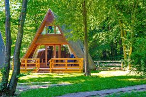Foto eines Nurdach-Ferienhauses auf einer Wiese zwischen Bäumen