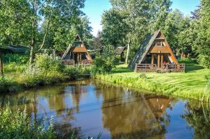 Foto von zwei Nurdachhäusern mit Terrasse an einem Teich