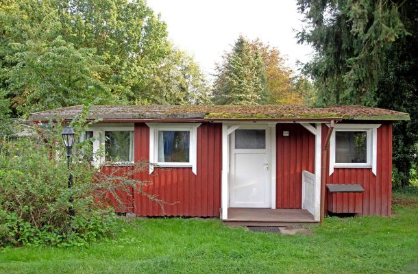 Typ A – Chalet 5 in roter Holzoptik mit weiß abgesetzten Fensterrahmen und überdachtem Eingangsbereich