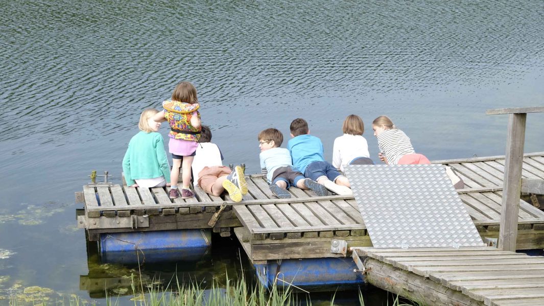 Foto von mehreren Kindern auf einem Holzsteg am Wasser