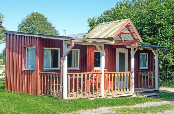 Typ A – Rotes Chalet 2 mit überdachter Holzveranda, weißen Fenstern und rotem Holzfassadenstil, gelegen auf grüner Wiese