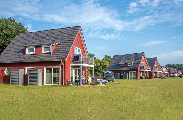 Typ G – Seewohnung 415 mit Balkon und Wiese im Vordergrund, mehrere Häuser im Hintergrund