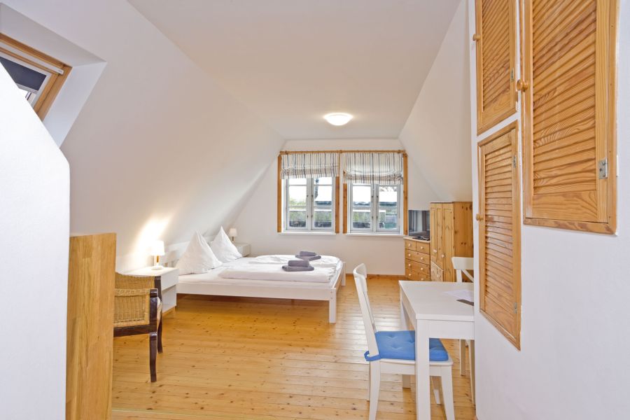 Foto eines gemütlichen Ferienzimmers mit Doppelbett und kleinem Esstisch