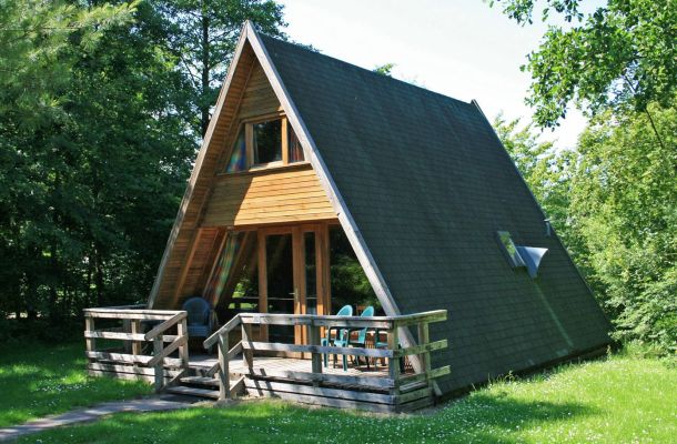 Typ E – Großes Nurdachhaus 302 mit dunklem Dach, Holzveranda und grünem Wiesenbereich