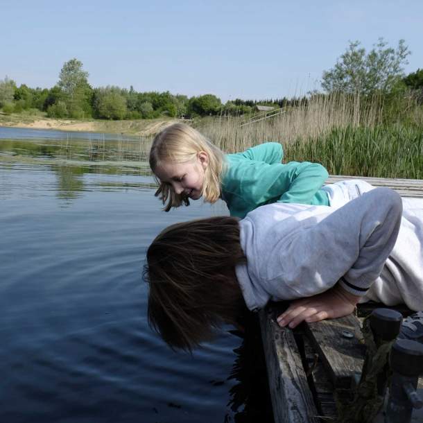 Foto von zwei Kinder, die am Geestsee vom Steg ins Wasser schauen.