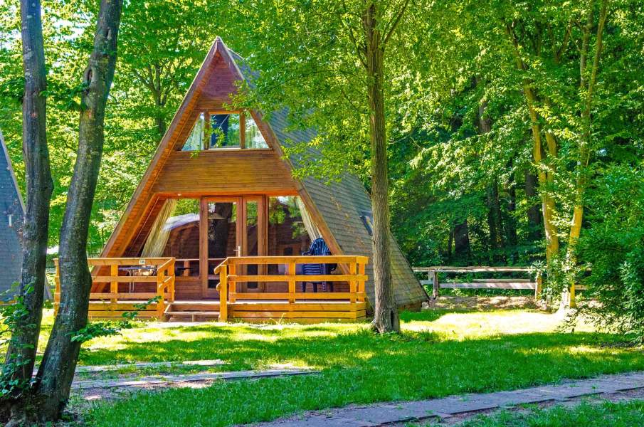 Foto eines Nurdach-Ferienhauses auf einer Wiese zwischen Bäumen