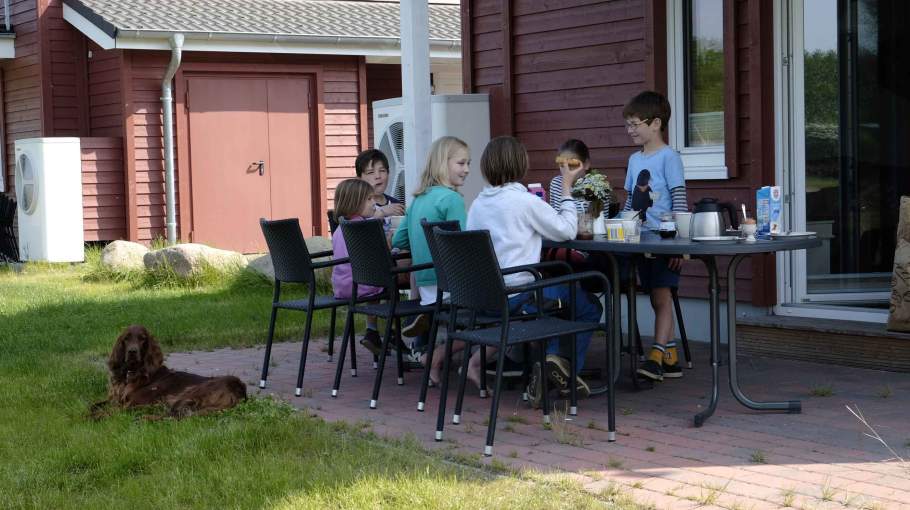 Foto einer Familie, die auf der Terrasse eines Ferienhauses frühstückt.
