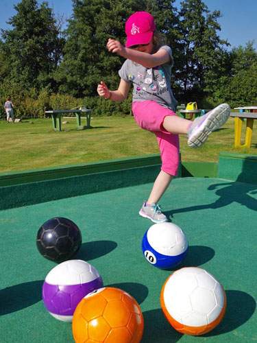 Foto von einem Kind, dass einen Fußball in Billard-Optik schießt