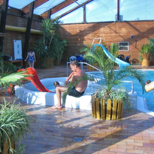 Foto eines Kinderbeckens mit roter Kinderrutsche ins Wasser.