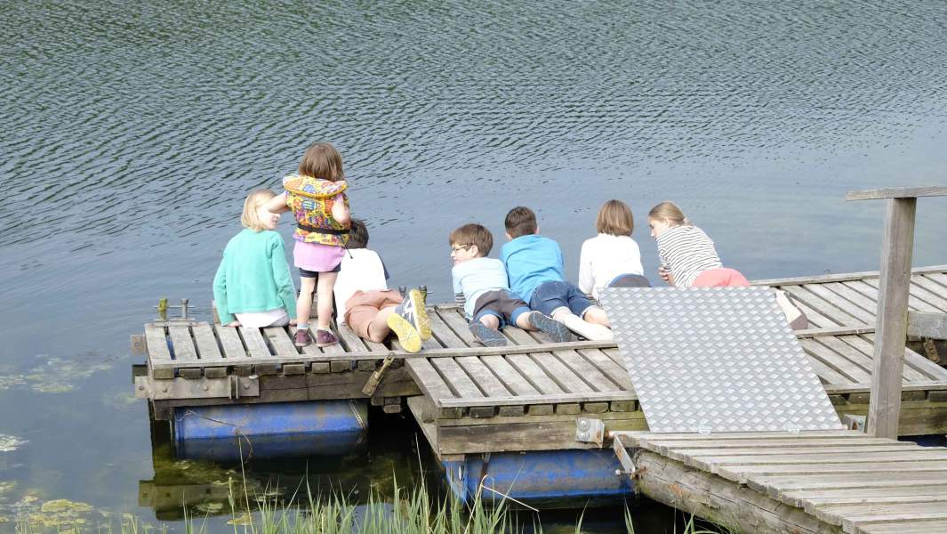 Foto von mehreren Kindern auf einem Holzsteg am Wasser