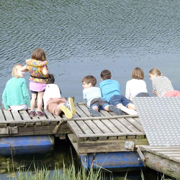 Foto von Kindern, die auf einem Steg am Wasser liegen